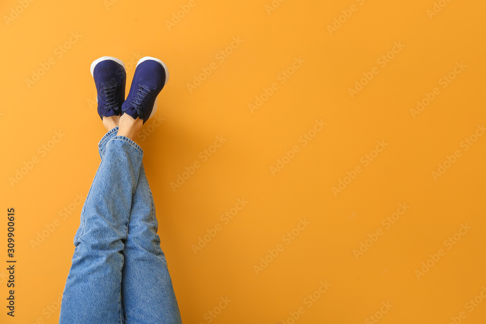 Young man in stylish shoes on color background