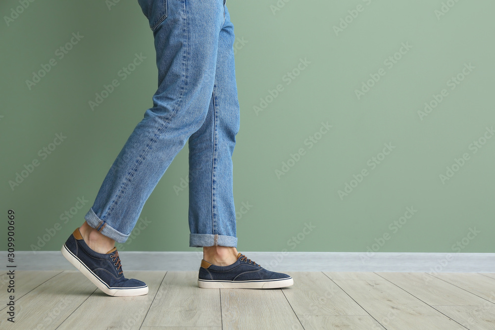 Young man in stylish shoes near color wall