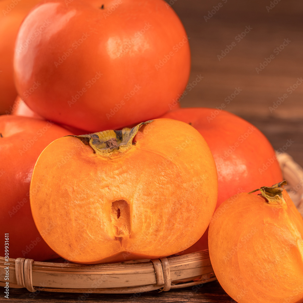 Fresh beautiful sliced sweet persimmon kaki on dark wooden table with red brick wall background, Chi