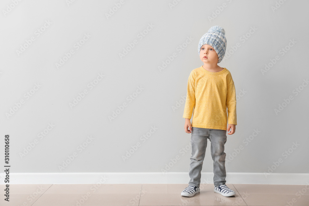 Portrait of cute little boy near light wall