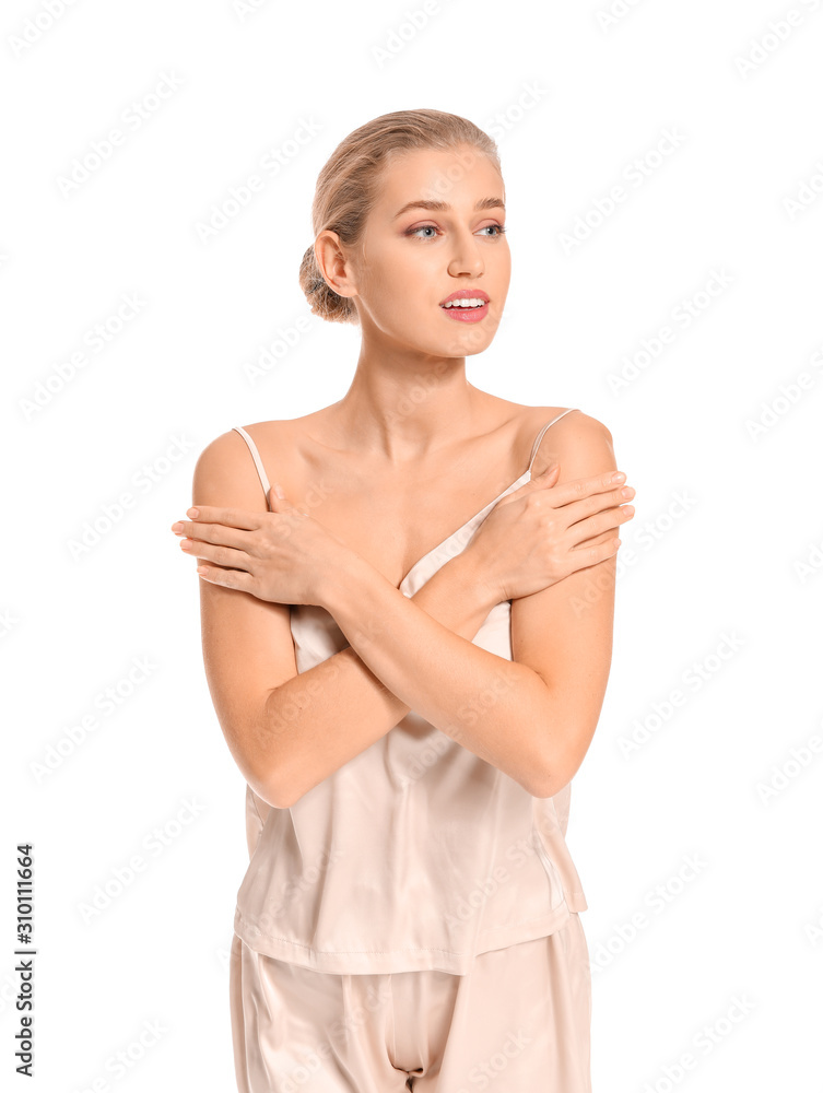 Beautiful young woman in pajamas on white background