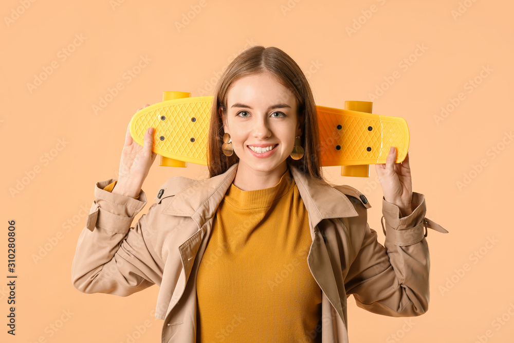 Stylish hipster girl with skateboard on color background