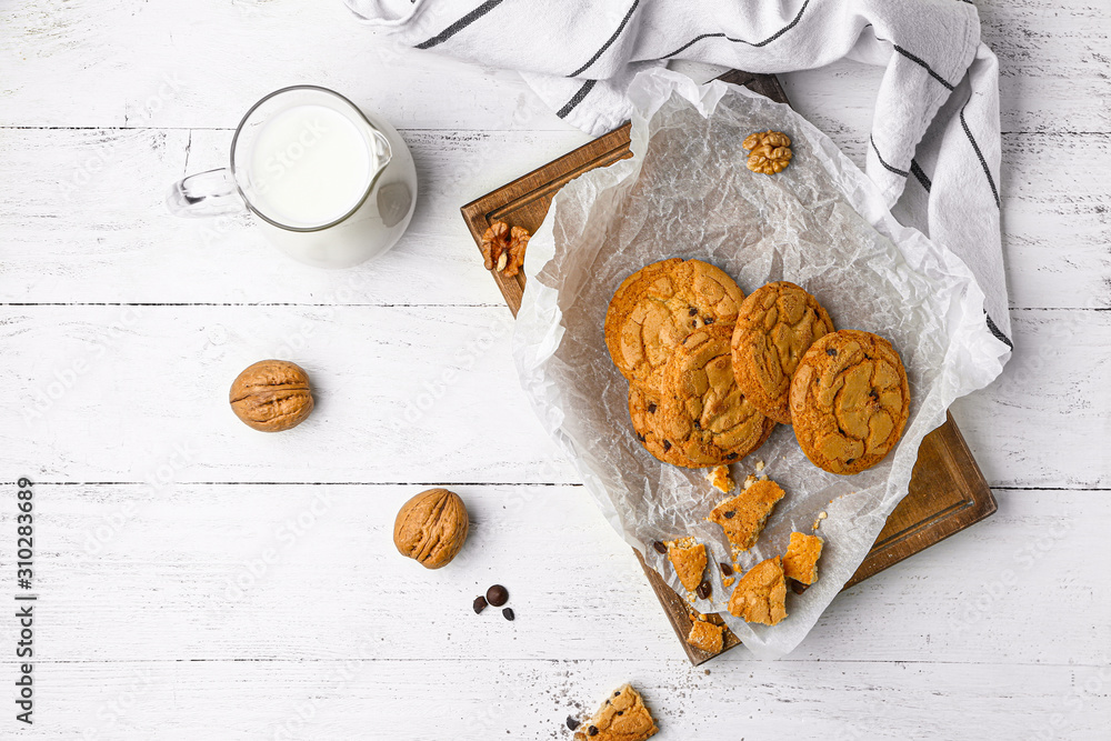 Tasty cookies with chocolate chips and milk on table