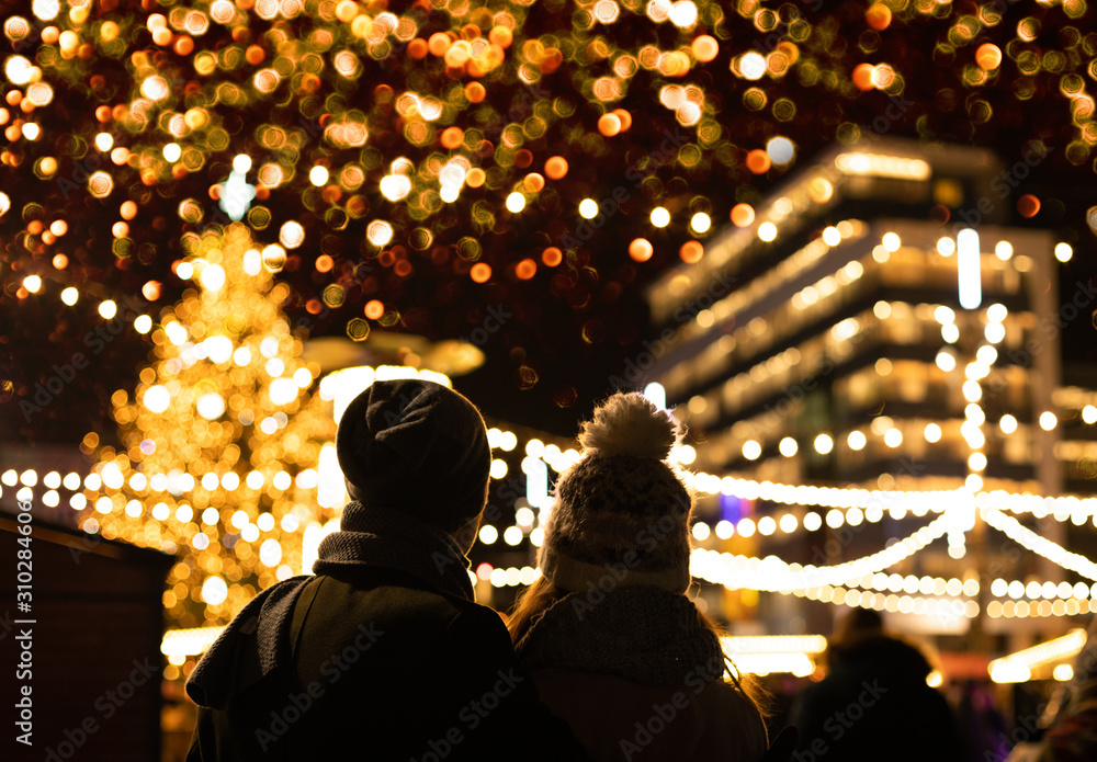 The couple are looking at the decorated Christmas market in the evening