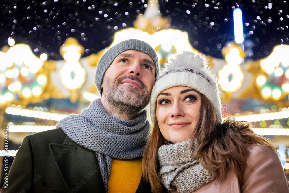 Loving couple on the background of winter holidays decorations during an evening walk around Christm