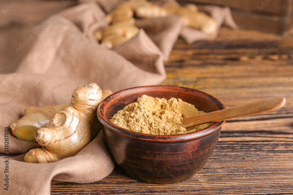 Bowl with ground ginger on wooden table