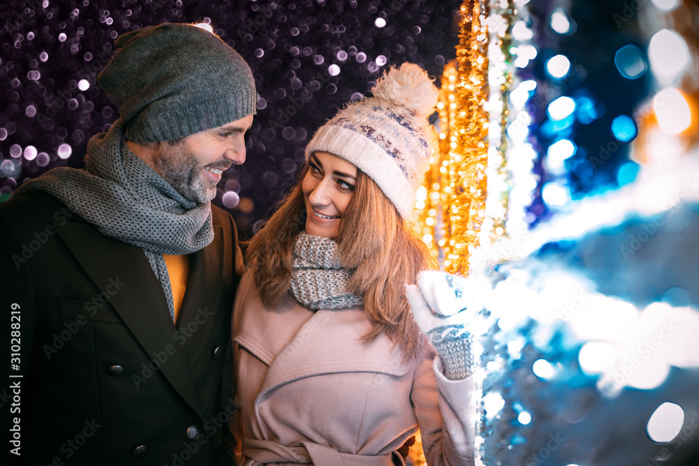 Happy couple walks on a street decorated for Christmas