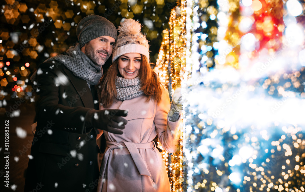 Happy couple walks on a street decorated for Christmas