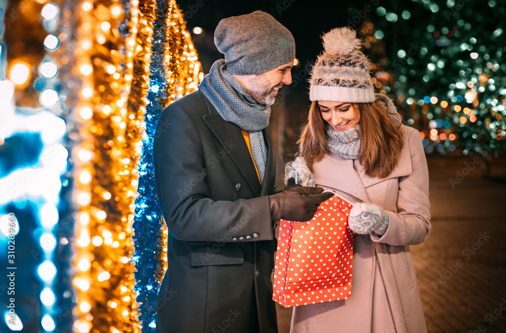 Couple with a Christmas gift after shopping walks on a decorated street