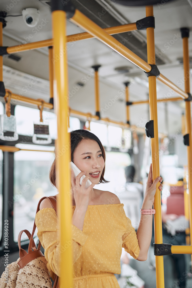 亚洲女孩在公交车上使用电话