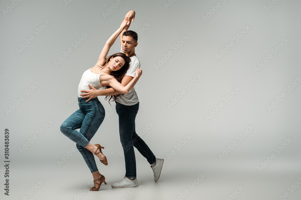 dancers with closed eyes dancing bachata on grey background