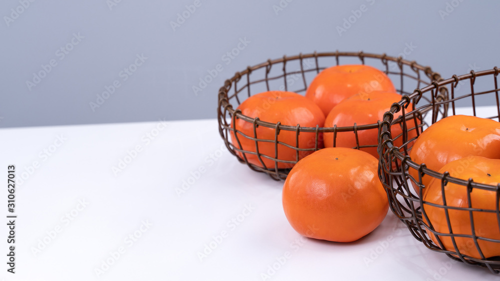 Fresh beautiful sliced sweet persimmon kaki isolated on white kitchen table with gray blue backgroun