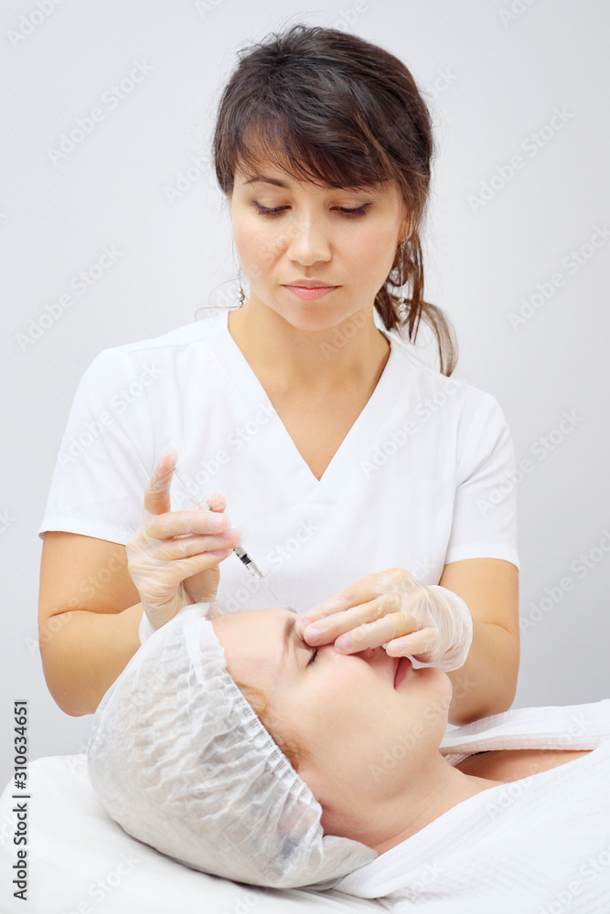 doctor-cosmetician carries out medical treatment injecting gel-like medicine under skin in beauty cl