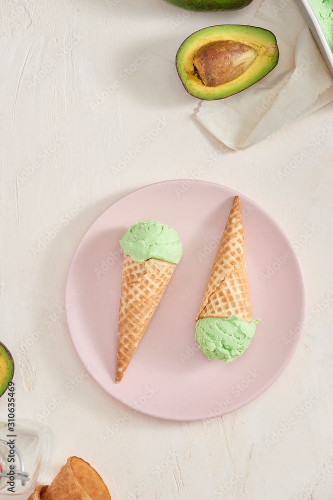 Green avocado ice cream scoops in wafle cones on white background. Copy space