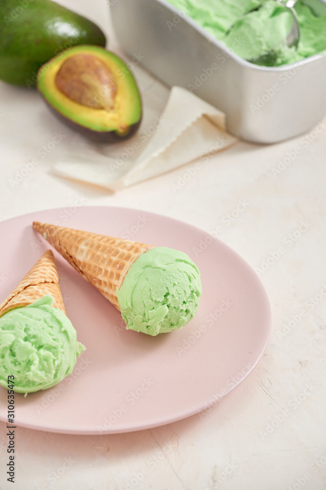 Green avocado ice cream scoops in wafle cones on white background. Copy space