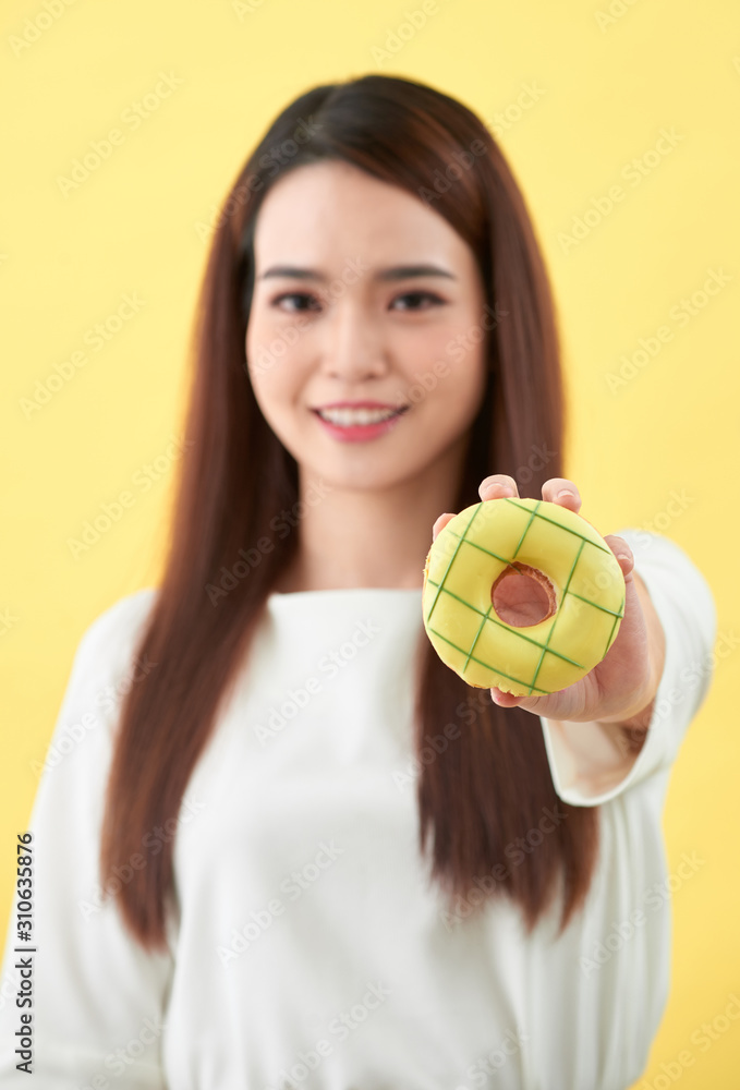 Close up portrait of a cute girl posing with donuts on yellow background