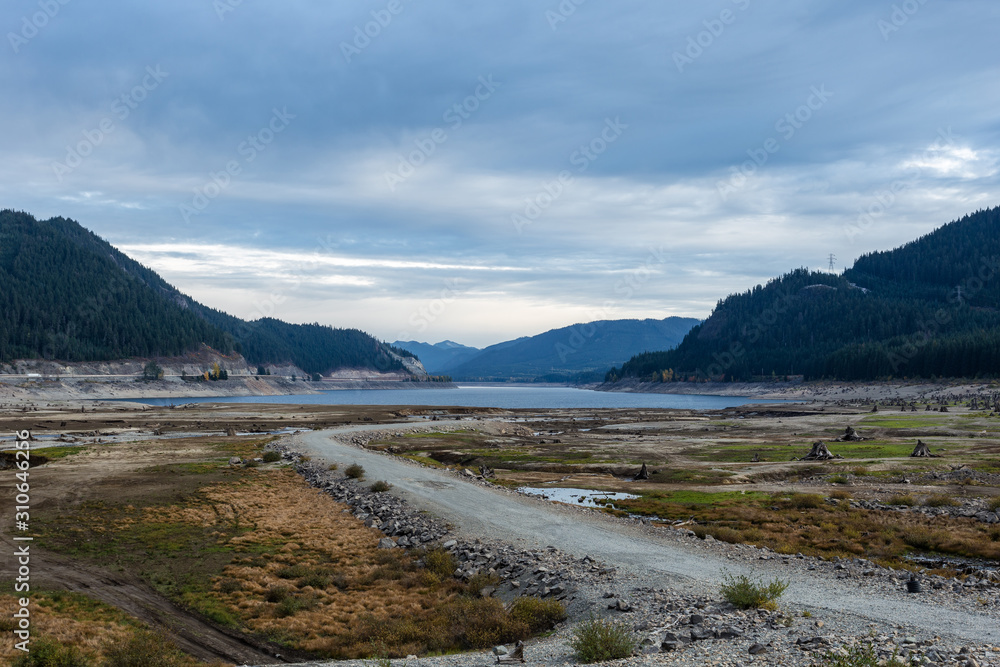 砾石和泥土小路穿过干涸的湖床，茂密的常绿森林覆盖着群山