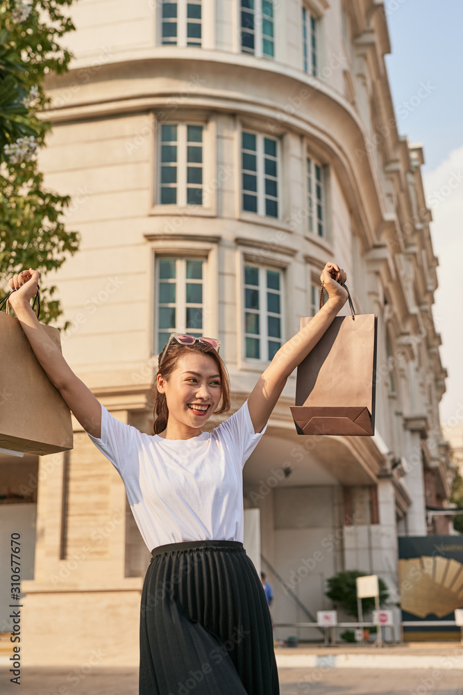 幸福的购物狂女人微笑着在街上跳舞。