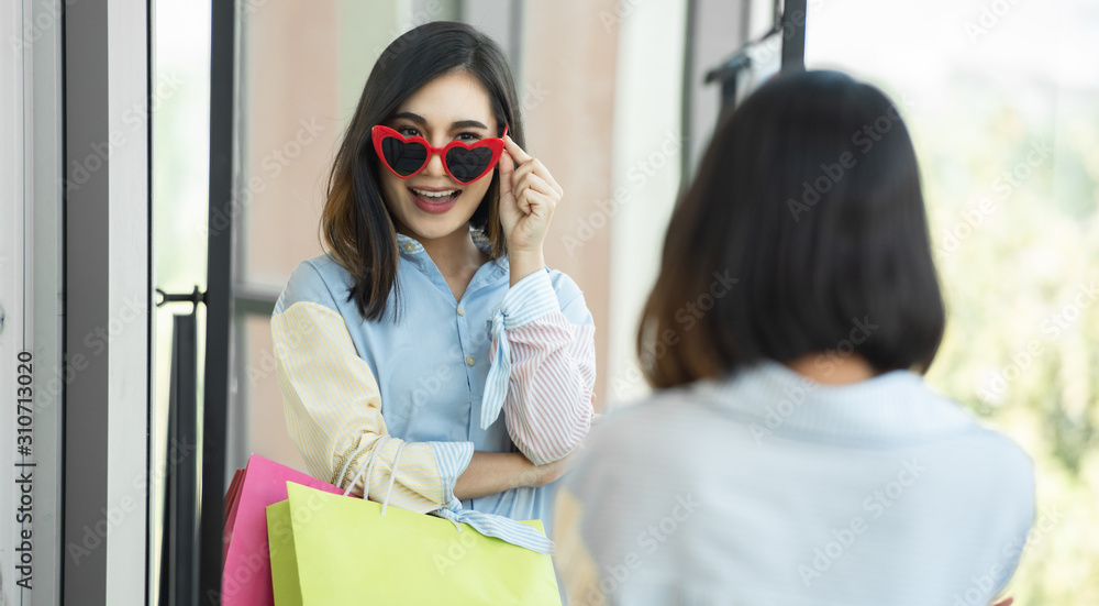 年轻的旅行购物女士拿着纸袋在购物中心买衣服。