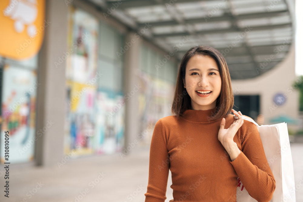 幸福、消费主义、销售和人的概念——面带微笑的年轻亚洲女性在你身边拿着购物袋