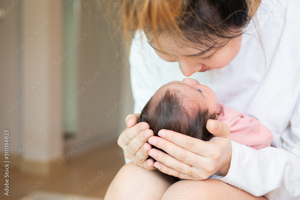 Asian young mother holding new born baby on hand touching nose with her love