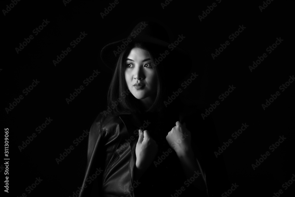 Black and white portrait of young Asian woman on dark background