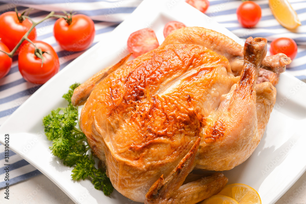 Plate with baked chicken on table