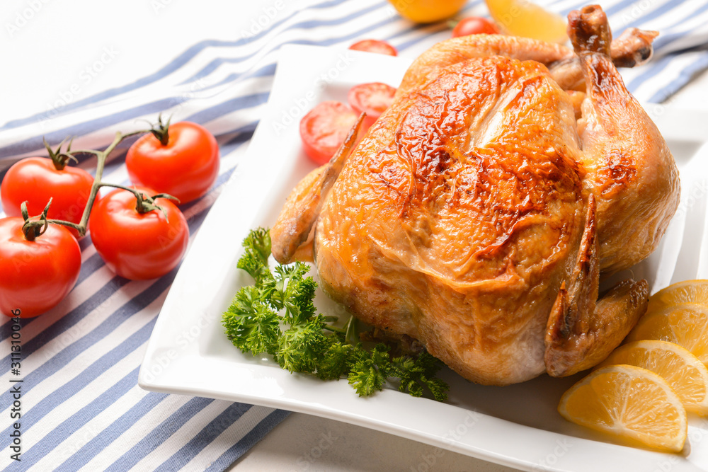 Plate with baked chicken on table