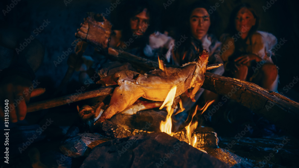 尼安德特人或智人家族在篝火上烹饪动物肉，然后食用。史前部落