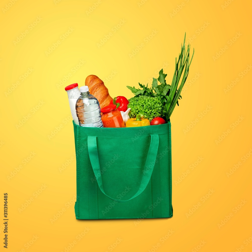 Bag full of groceries on wooden desk with pastel background