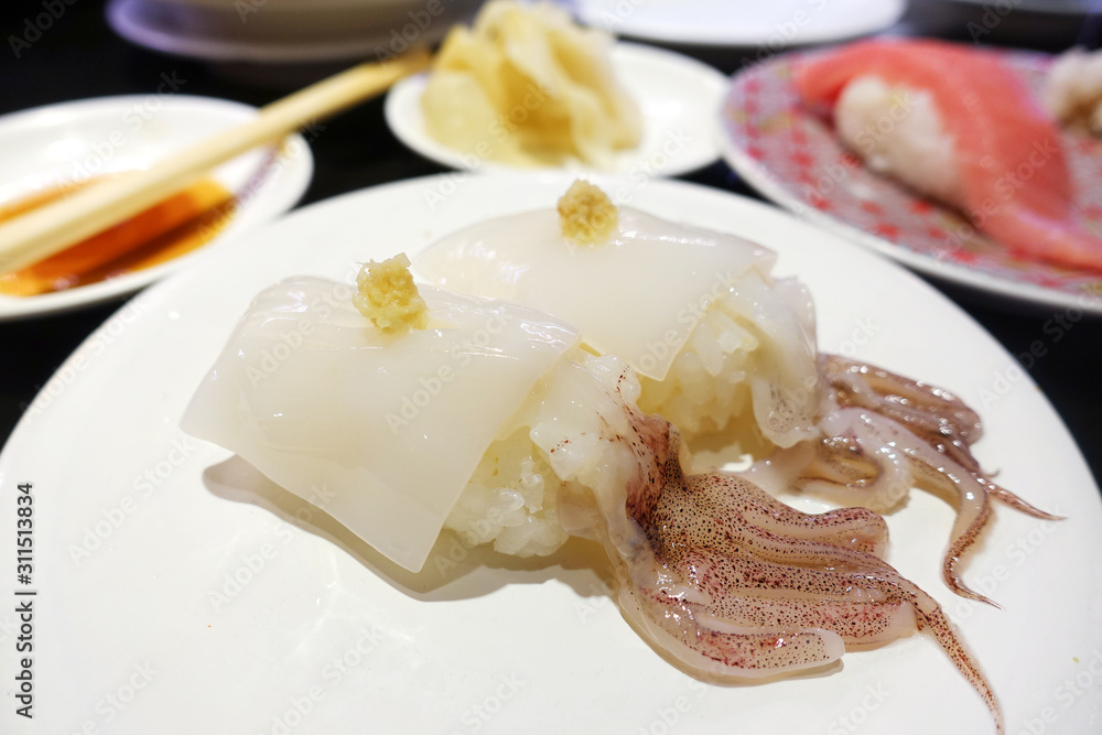 Japanese raw squid nigiri with ginger on a white plate