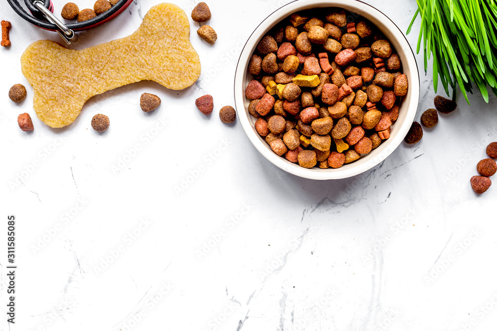 dry dog food in bowl on stone background top view