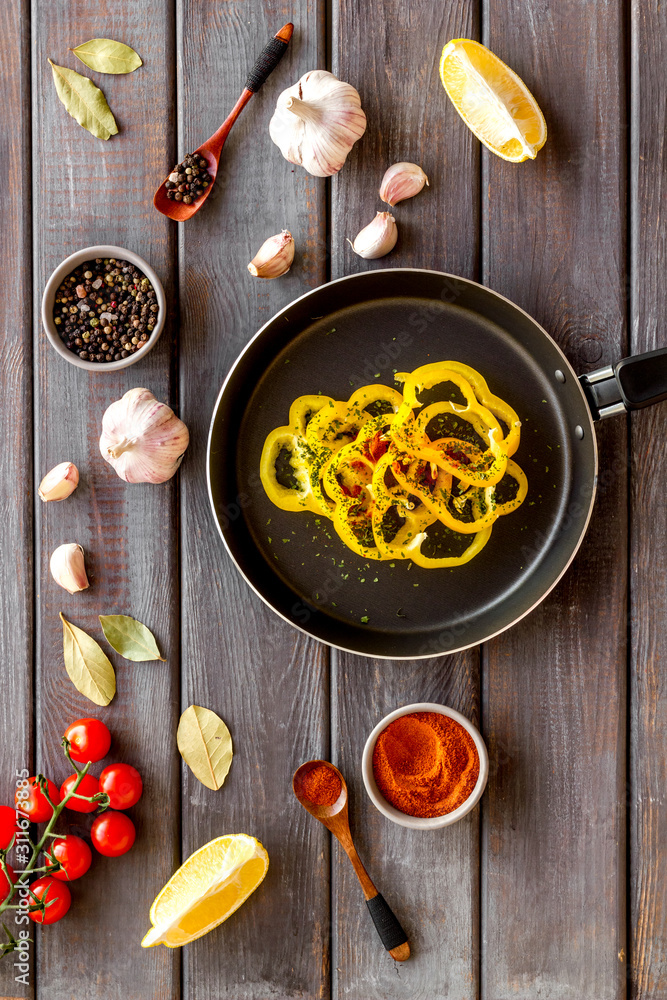 Cooking food concept. Pasta on frying pan near spices and vegetables on dark wooden background top-d