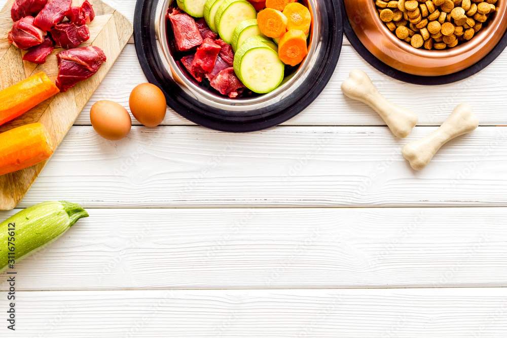 Ingredients of dry feed for dogs - meat, vegetables - near bones on white wooden background top-down