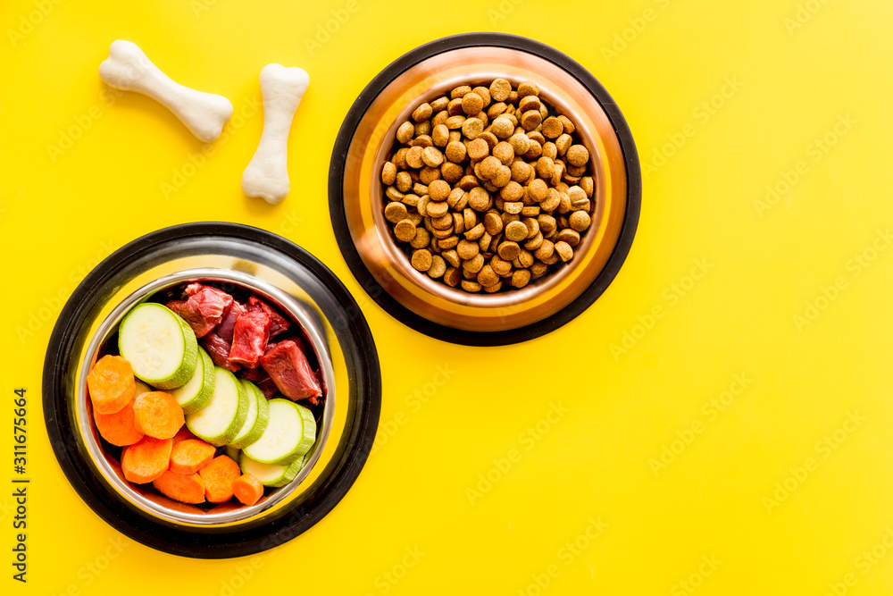 Ingredients of dry feed for dogs - meat, vegetables - near bones on yellow background top view copy 