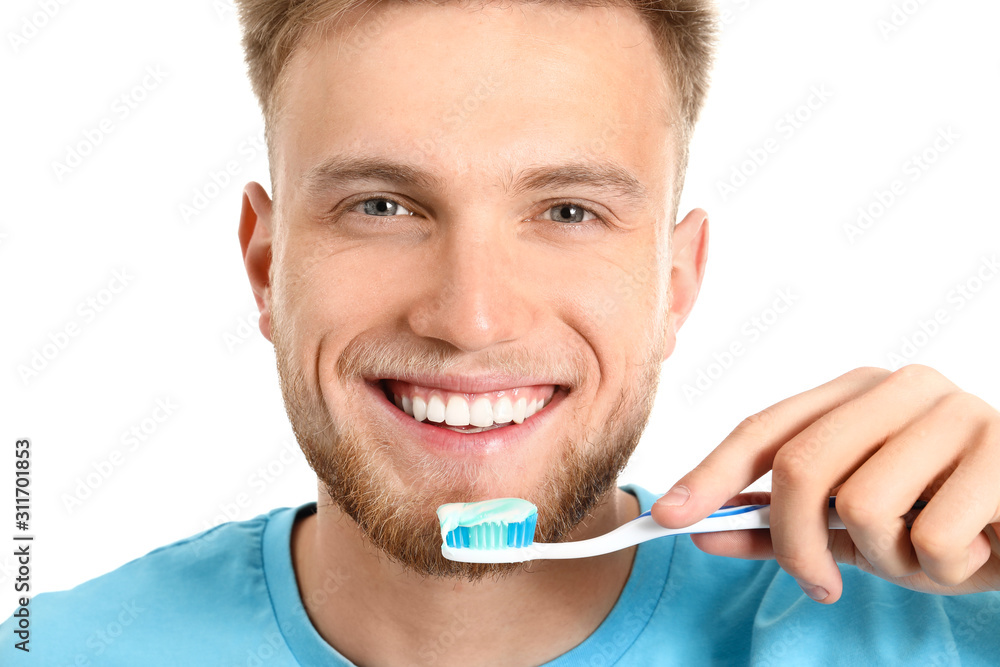 Young man brushing teeth on white background