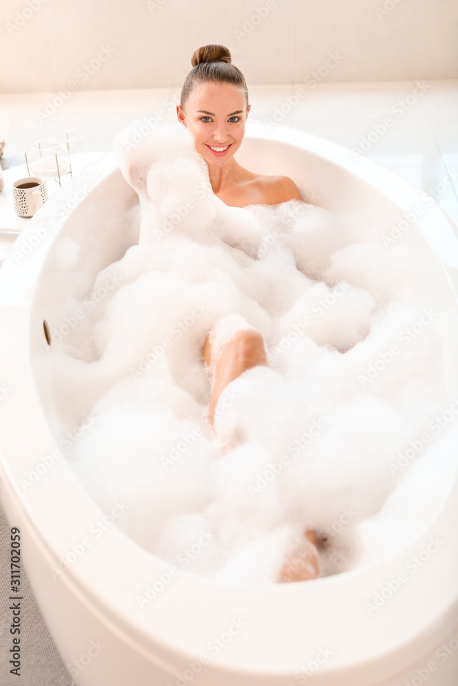 Beautiful young woman relaxing in bathtub