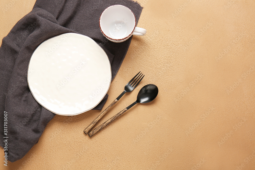 Empty plate, cup, napkin and cutlery on color background