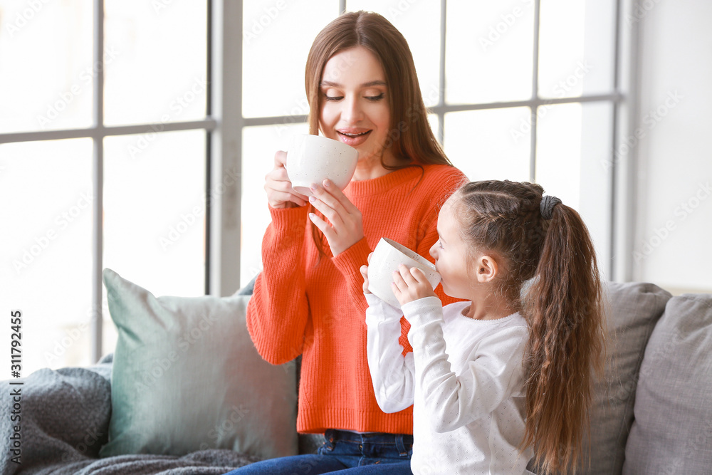 年轻女子和她的小女儿在家一起喝茶