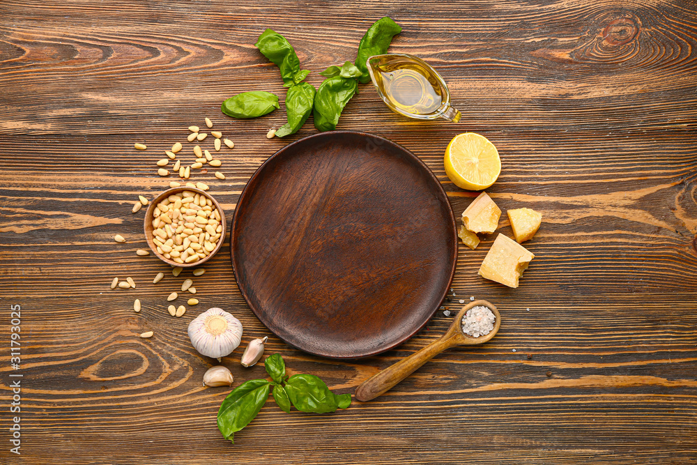 Ingredients for pesto sauce and plate on wooden background