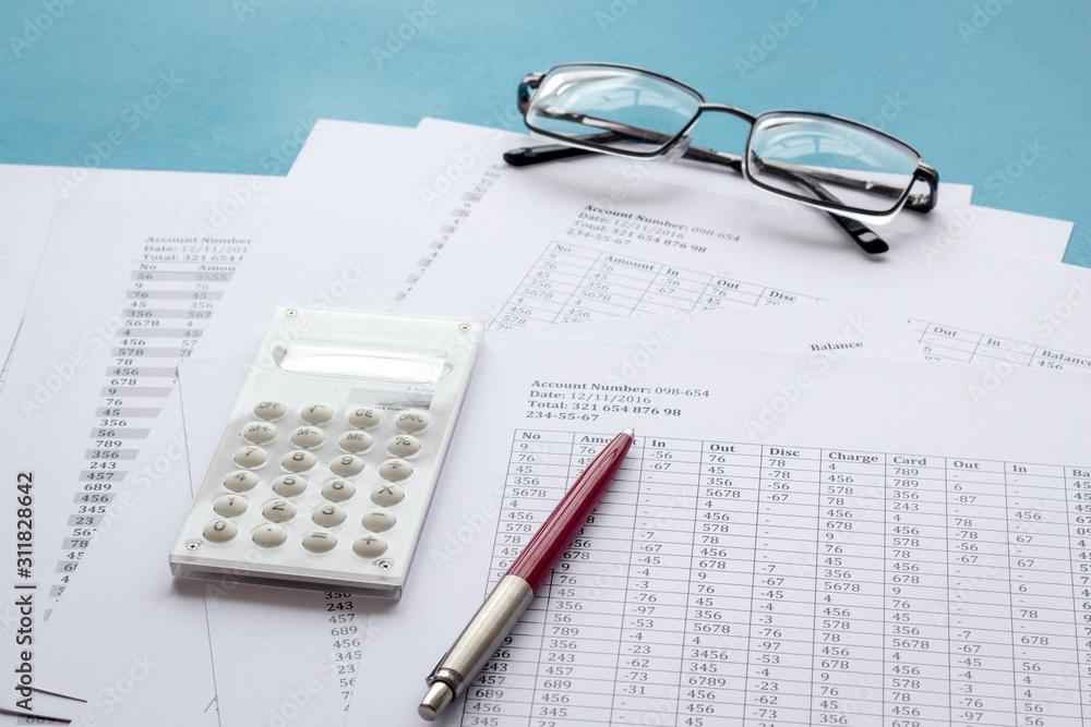 Taxes calculation concept. Financial documents, calculator, glasses on blue background