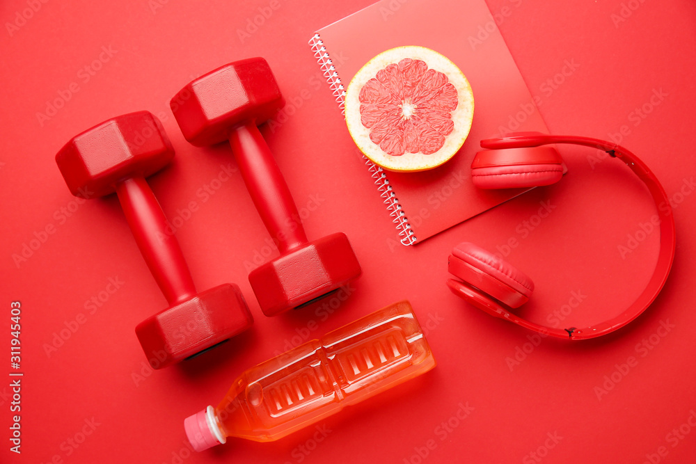 Dumbbells with notebook, headphones grapefruit and bottle of water on color background