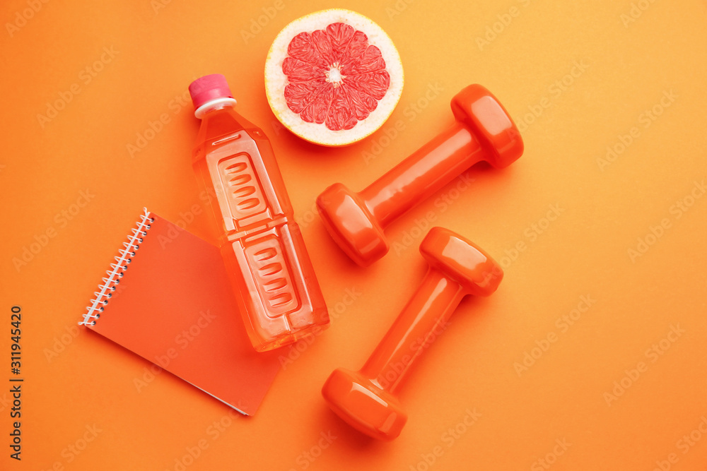 Dumbbells with notebook, grapefruit and bottle of water on color background