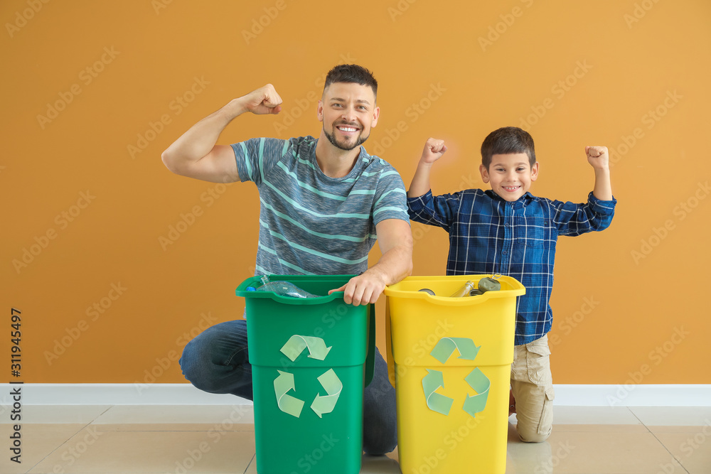 Happy father and son with containers for garbage on color background. Concept of recycling