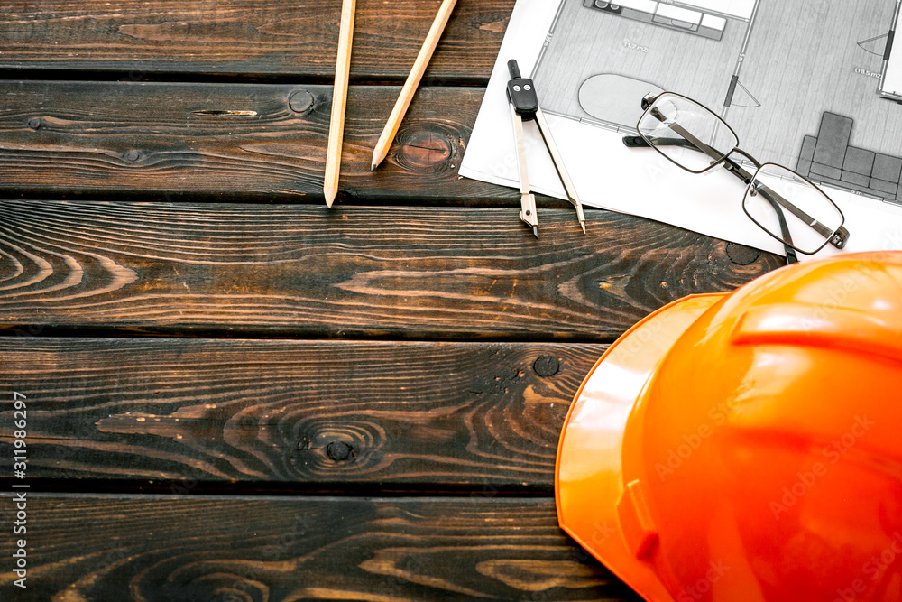 Construction concept. Helmet and blueprints on dark wooden background copy space