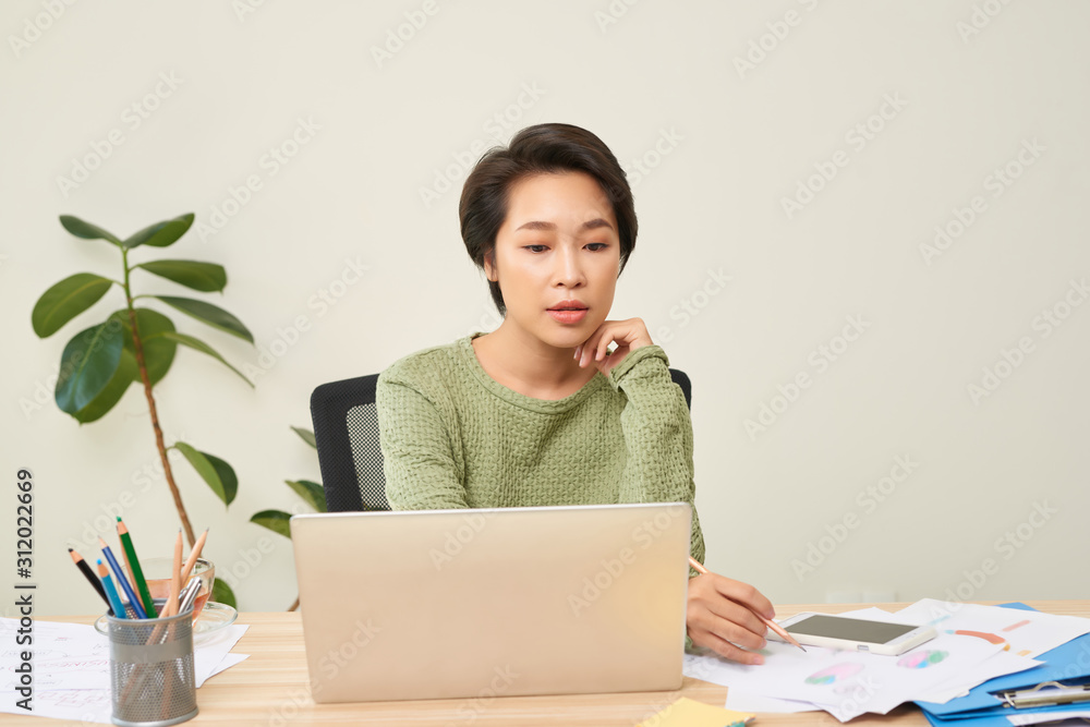 Young Asian business woman entrepreneur using computer looking at screen working in internet