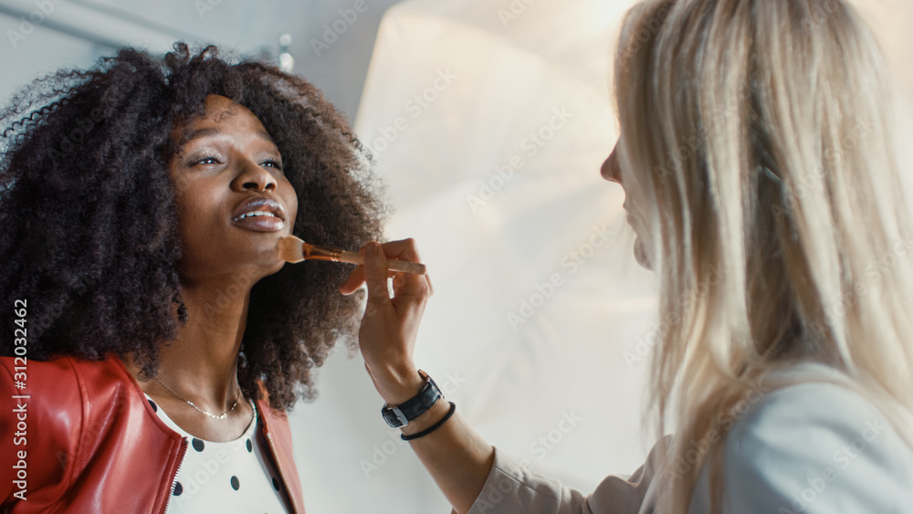 照片拍摄的后台：化妆师为美丽的黑人模特化妆。在后台