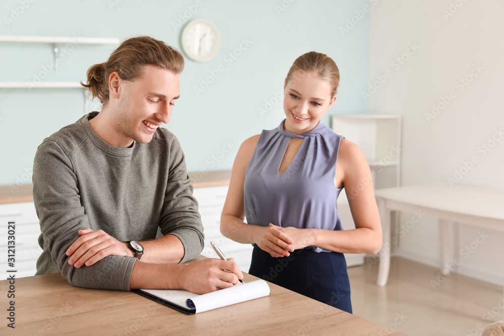 Young man signing a sale and purchase contract in his new house