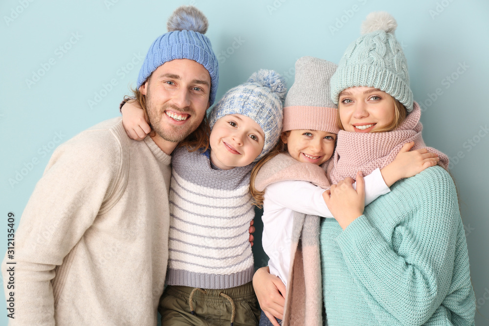 Happy family in winter clothes on color background