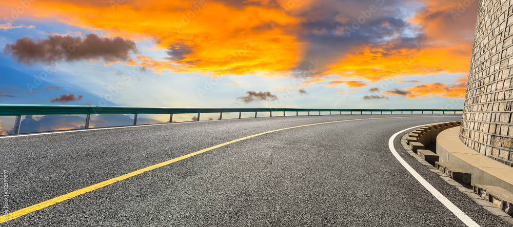 沥青公路和日落时美丽的彩云。全景。